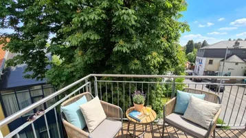 Gemütlicher Balkon mit Sitzgelegenheiten und Blick ins Grüne, ideal zum Entspannen im Freien.