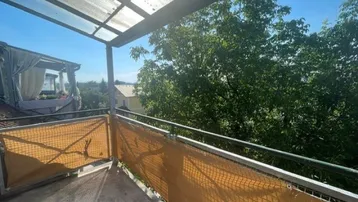 Überdachter Balkon mit Blick ins Grüne und auf die Umgebung, ideal für sonnige Tage.