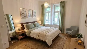 Helles Schlafzimmer mit Holzboden, großem Bett und Fenster mit grünen Vorhängen.