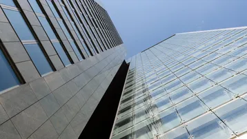 Moderne Hochhäuser mit Glas- und Steinfassaden, die sich zum blauen Himmel erheben und eine beeindruckende Architektur zeigen.
