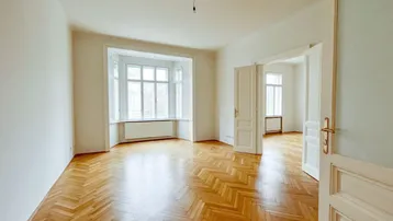 Helles Zimmer mit Fischgrätparkett, Erkerfenster und weißen Wänden, bereit zur individuellen Gestaltung.
