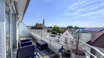 Geräumige Dachterrasse mit Sitzgelegenheiten und weitem Blick über die Stadt und Kirchturm.