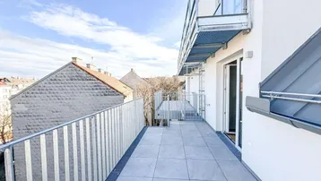Geräumiger Balkon mit modernen Fliesen und Metallgeländer, bietet einen weiten Blick auf die Umgebung.