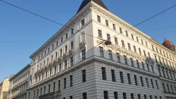 Eindrucksvolles Eckgebäude mit klassischer Architektur und zahlreichen Fenstern unter blauem Himmel.