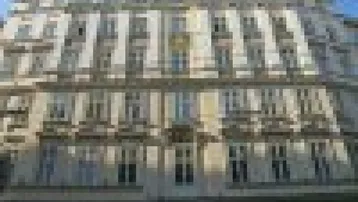 Die Fassade des Gebäudes zeigt klassische Architektur mit vielen Fenstern und mehreren Stockwerken.