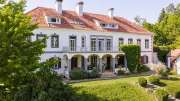 Elegante Villa mit klassischer Architektur, rotem Ziegeldach und gepflegtem Vorgarten.