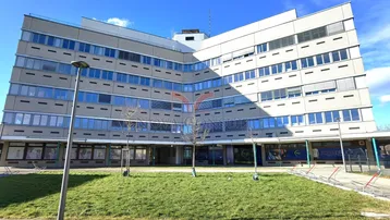 Großes Bürogebäude mit moderner Architektur und Grünfläche davor unter blauem Himmel.