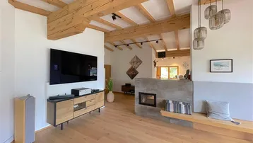 Geräumiges Wohnzimmer mit Holzboden, modernem Kamin und integriertem TV-Bereich.