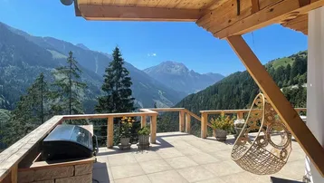Geräumige Terrasse mit Grillbereich und atemberaubendem Bergblick, ideal für Entspannung im Freien.