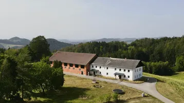 Ländliches Anwesen mit zwei Gebäuden, umgeben von Wäldern und Feldern, mit weitem Blick auf die Hügellandschaft.