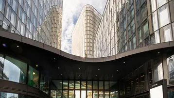 Moderne Bürogebäude mit geschwungenen Glasfassaden und einem markanten Eingangsbereich unter einem Vordach.