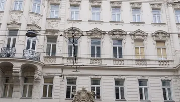 Historische Fassade eines Altbaus mit reich verzierten Details und Geschäften im Erdgeschoss.