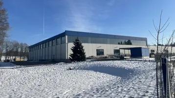 Großes Industriegebäude mit blauen Dächern und Fassaden in einer verschneiten Landschaft unter blauem Himmel.