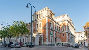 Historisches Gebäude mit roter Backsteinfassade und weißen Steinakzenten an einer belebten Straße.