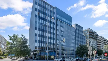 Modernes Bürogebäude mit Glasfassade und vielen Fenstern in städtischer Umgebung.