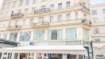Historisches Gebäude mit klassischer Fassade und einem belebten Straßencafé im Erdgeschoss.