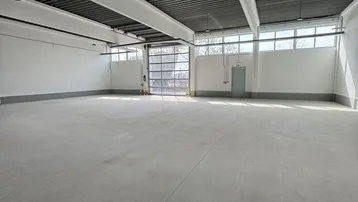 Geräumige, leere Industriehalle mit hohen Decken, Betonboden und großen Fenstern, bereit zur Nutzung.