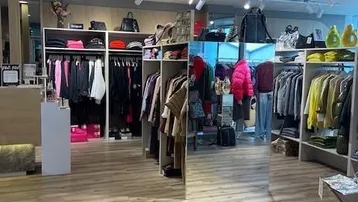 Heller und moderner Verkaufsraum mit Holzfußboden und vielfältigen Präsentationsmöglichkeiten für Kleidung.