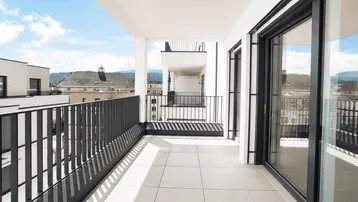 Geräumiger Balkon mit Blick auf die moderne Wohnanlage und die umliegende Landschaft.
