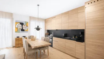 Moderne Küche mit hellen Holzfronten, schwarzer Arbeitsplatte und integriertem Essbereich.
