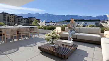 Geräumige Dachterrasse mit modernen Outdoor-Möbeln, Bergblick und viel Sonnenlicht.