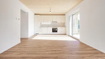 Heller offener Wohn-Essbereich mit integrierter Küche, Laminatboden und Holzbalkendecke.