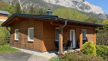 Blockhaus mit Holzfassade und Bergblick unter blauem Himmel.