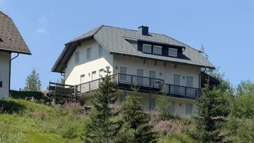 Attraktives Haus am Hang mit mehreren Balkonen und Blick auf die umliegende Berglandschaft.