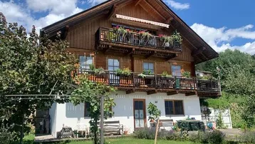 Traditionelles Holzhaus im Chalet-Stil mit mehreren Balkonen und einem gepflegten Gartenbereich.