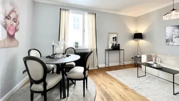 Helles Wohn- und Esszimmer mit Holzboden, modernen Möbeln und dekorativen Bildern.