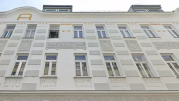 Historische Fassade eines Wohngebäudes mit dekorativen Stuckelementen und Dachgauben.