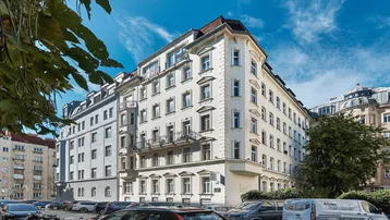 Mehrstöckiges Wohngebäude mit klassischer Architektur und Balkonen an einer städtischen Straße.