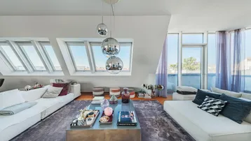 Helles Wohnzimmer im Dachgeschoss mit großen Dachfenstern und moderner Einrichtung.