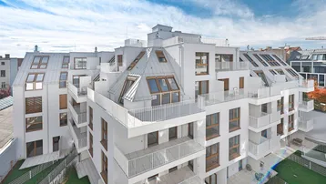 Modernes Wohngebäude mit vielen Balkonen und Dachterrassen unter blauem Himmel.