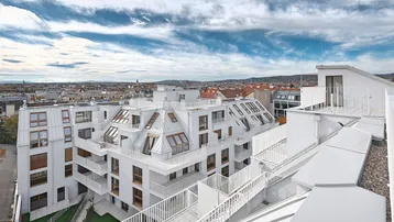 Weitläufiger Blick auf das moderne Wohngebäude mit Dachterrassen und der umliegenden Stadt.