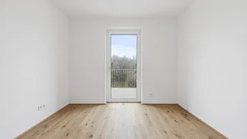 Leeres Schlafzimmer mit Holzboden und französischem Balkon, bietet Blick ins Grüne.