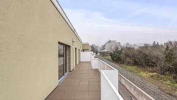 Geräumiger Balkon mit Fliesenboden und Blick auf die Umgebung und andere Gebäude.
