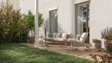 Gemütliche Holzterrasse mit Gartenmöbeln, umgeben von Rasen und blühenden Sträuchern.