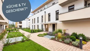 Moderne Wohnanlage mit gepflegtem Gartenbereich und Zugang zu den Eingängen der Gebäude.