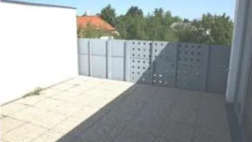 Geräumige, gepflasterte Terrasse mit Sichtschutz und Blick ins Grüne.