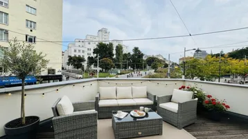 Möblierte Dachterrasse mit bequemen Sitzgelegenheiten und Blick auf die Stadt.