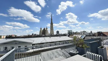 Geräumige Dachterrasse mit Sitzgelegenheiten und beeindruckendem Blick auf die Wiener Innenstadt und den Stephansdom.