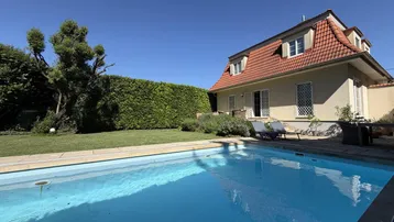 Großzügiger Gartenbereich mit privatem Pool und sonniger Liegewiese vor dem charmanten Haus.
