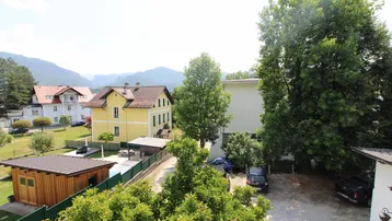 Weitläufiger Blick über die Nachbarschaft mit Häusern, Bäumen und Bergen im Hintergrund.
