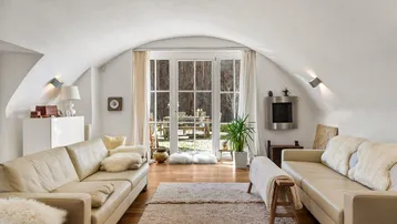 Helles Wohnzimmer mit gewölbter Decke, Holzboden und Zugang zu einem charmanten Gartenbereich.