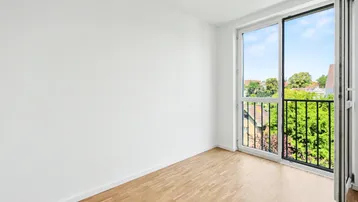 Helles Zimmer mit Parkettboden und einem französischen Balkon mit Blick ins Grüne.