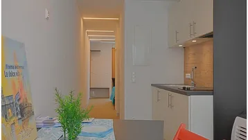 Kleiner Wohnbereich mit integrierter Küchenzeile und Blick in den Flur.