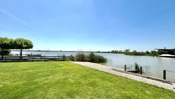 Gepflegte Rasenfläche am Seeufer mit Blick auf das Wasser und Boote.