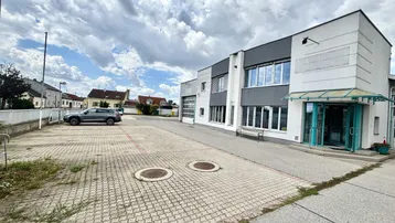 Modernes Geschäftsgebäude mit großem Parkplatz und klarem Himmel an einem sonnigen Tag.