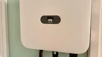 Photovoltaik-Wechselrichter an einer hellgrünen Wand installiert.